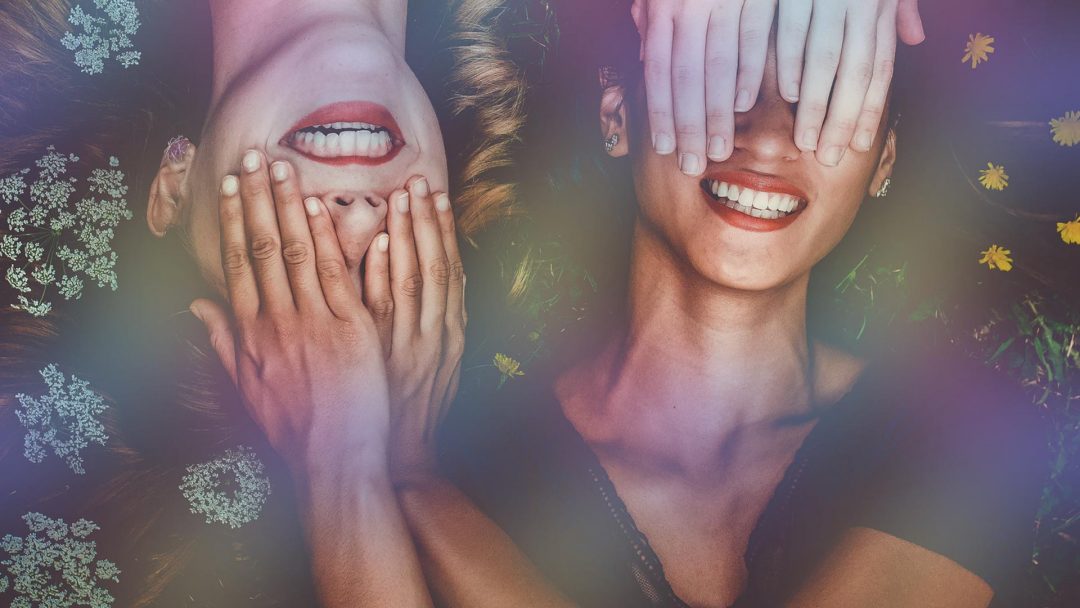 Two women are smiling and one is holding a toothbrush.